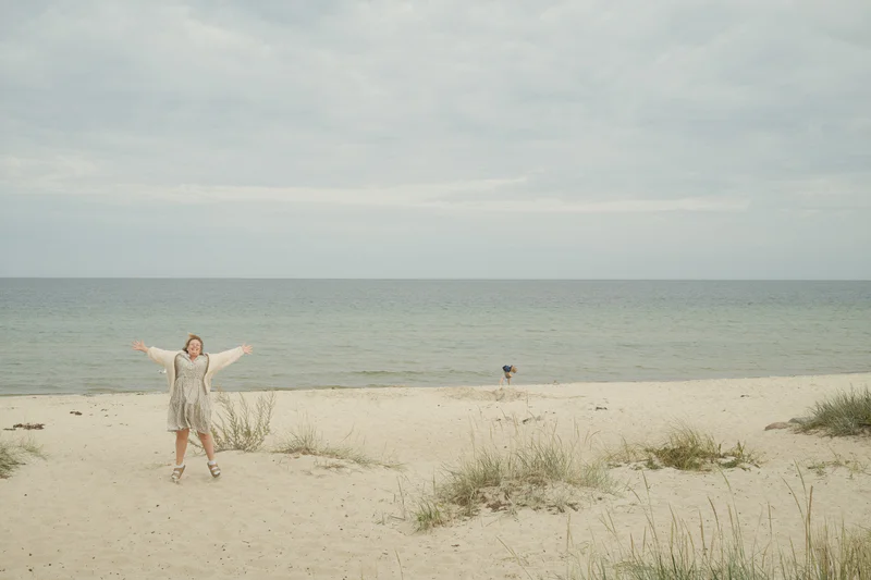 a photograph of a woman in a white dress standing on a beach