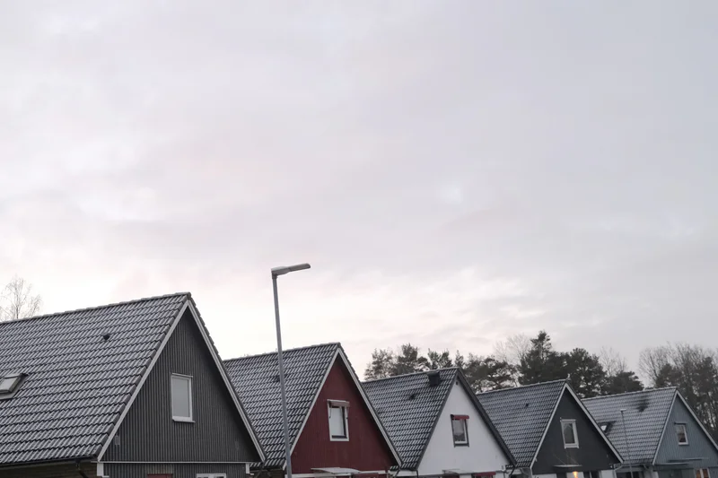 a photograph of a row of houses with a clock tower in the background